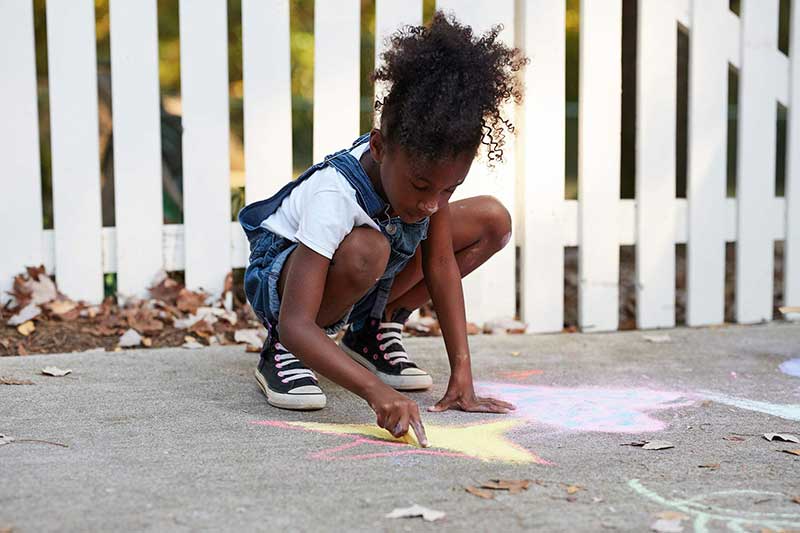 girl drawing with sidewalk chalk